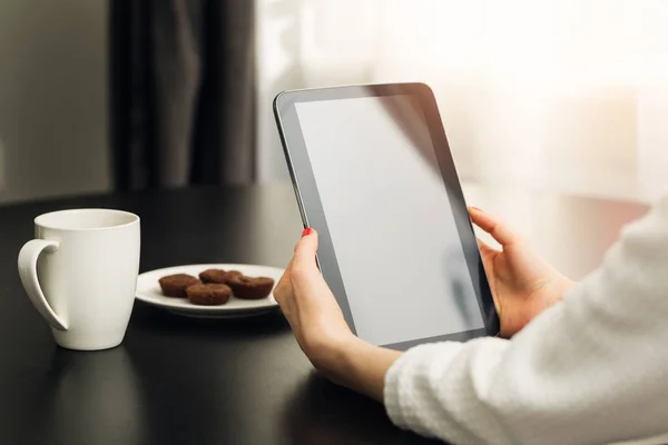 Женщина сидит за столом дома и использует цифровую электронную книгу — стоковое фото