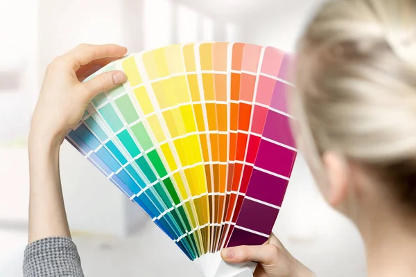 Vrouw huis interieur verf kleur selecteren uit staal catalogus — Stockfoto