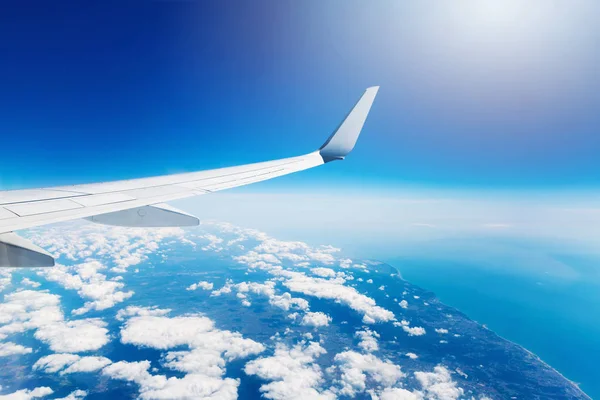 Wing of an airplane flying high in the sky above the clouds — Stock Photo, Image