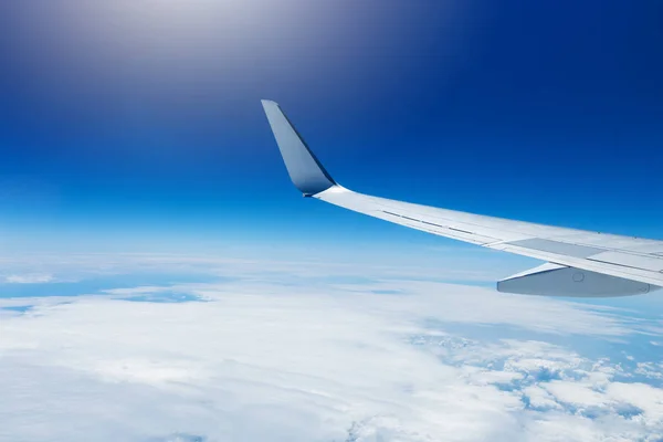 Wing of an airplane flying high in the sky above the clouds — Stock Photo, Image