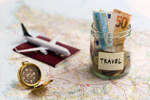travel concept - money savings, compass and passport on a map
