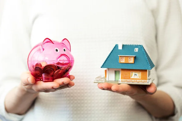 Savings for new family house concept - piggy bank and house scale model in hands — Stock Photo, Image