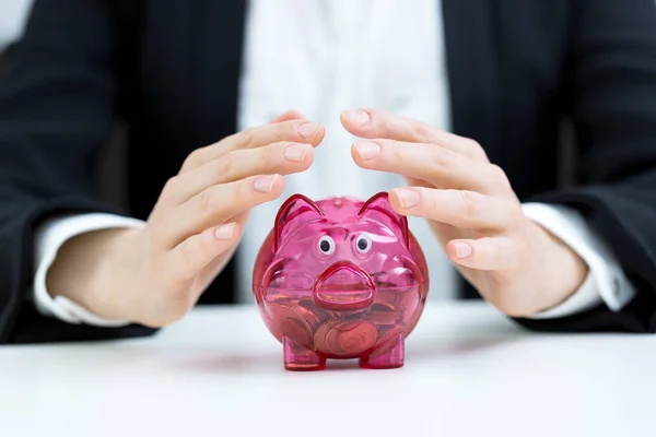 Business savings concept - businesswoman covering piggy bank with hands — Stock Photo, Image