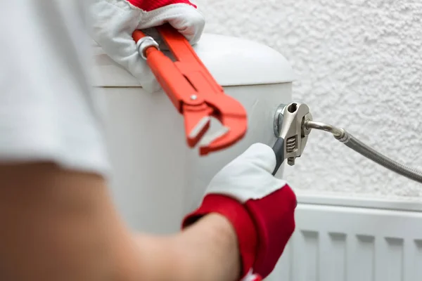 Klempner verlegt Rohr mit Schraubenschlüssel in Wassertoilette — Stockfoto