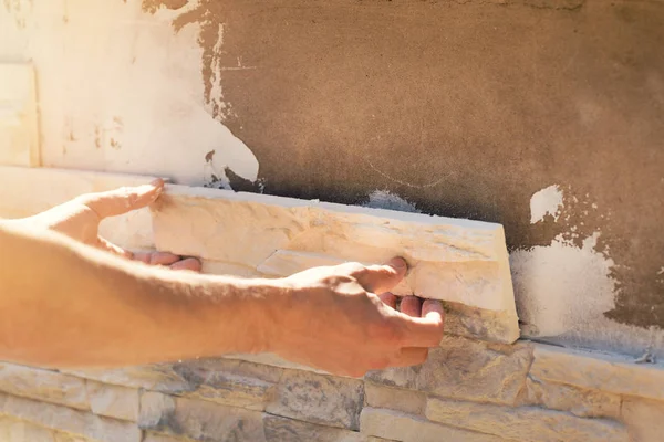 Рабочий устанавливает декоративную каменную плитку на фасад дома — стоковое фото