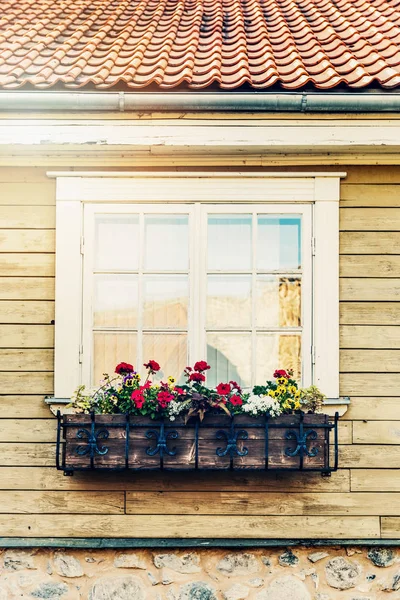Blumenkasten hängt vor altem Holzhausfenster — Stockfoto
