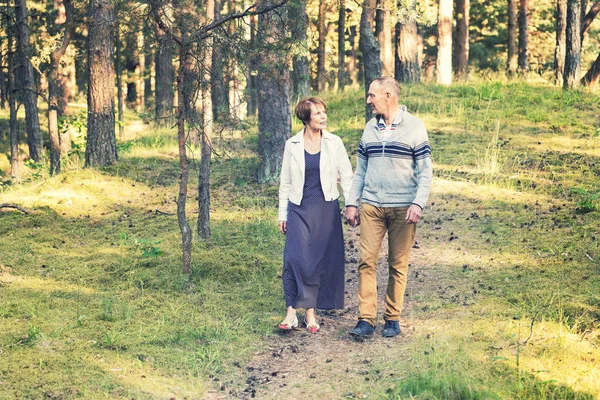 Seniorenpaar läuft händchenhaltend auf Waldweg — Stockfoto