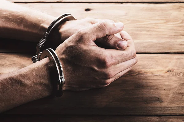 Ellerini masanın üzerine kelepçe ile