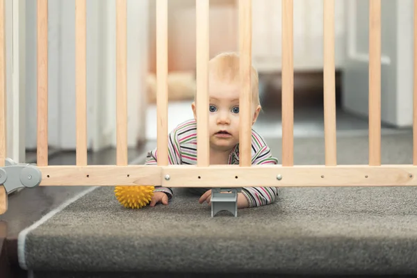 Bébé jouant avec la balle derrière les barrières de sécurité — Photo