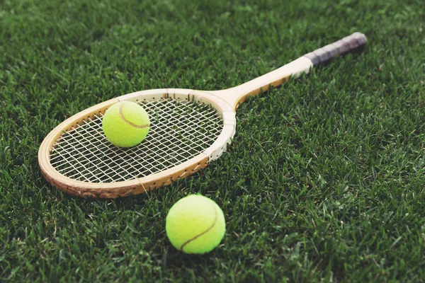 Raquete de tênis de madeira vintage na grama com bolas — Fotografia de Stock