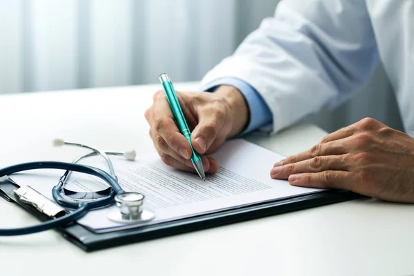 Médico escrever documentos na mesa no escritório de clínicas — Fotografia de Stock