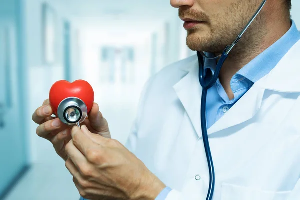 Cardiologista verificando coração vermelho com estetoscópio. conceito de cardiologia — Fotografia de Stock