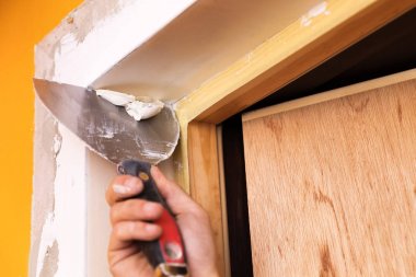 yeni bir kapı çevresinde sıva spatula ile yama