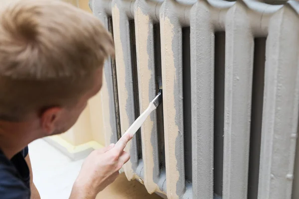 Trabajador pintando un radiador de calefacción con pincel — Foto de Stock