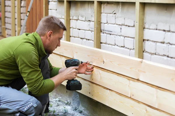 Trabajador de la construcción de la instalación de nuevas tablas de madera en la antigua fachada de ladrillo casa —  Fotos de Stock