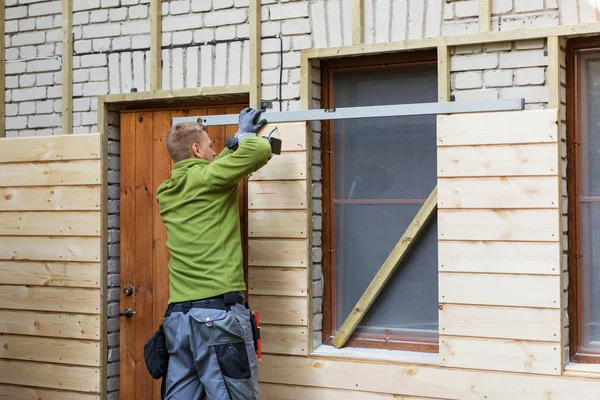 Arbeiter restaurieren alte Ziegelhausfassade mit neuen Holzbohlen — Stockfoto