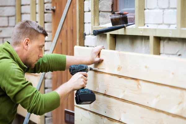 Byggnadsarbetare installerar träplankor på hus fasad — Stockfoto