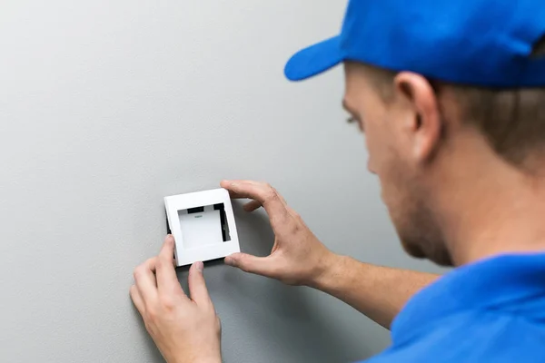 Eletricista em azul uniforme instalar interruptor de luz na parede — Fotografia de Stock
