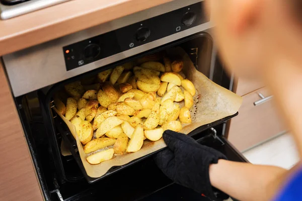 Mulher removendo bandeja de batatas preparada fora do forno — Fotografia de Stock