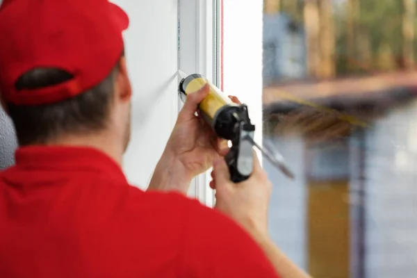 Trabajador aplicando calafateo alrededor del marco de la ventana — Foto de Stock