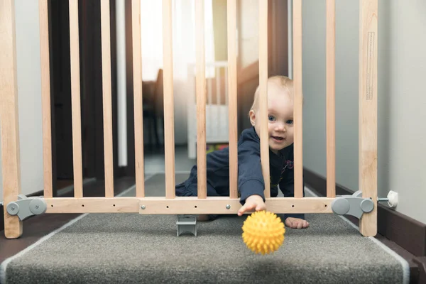 Bambino buttando via la palla attraverso i cancelli di sicurezza di fronte alle scale — Foto Stock