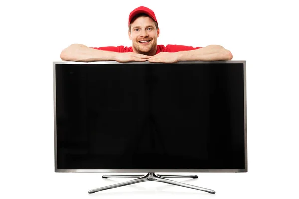 Vendedor sorrindo em uniforme vermelho sobre grande tela de tv em branco isolado — Fotografia de Stock