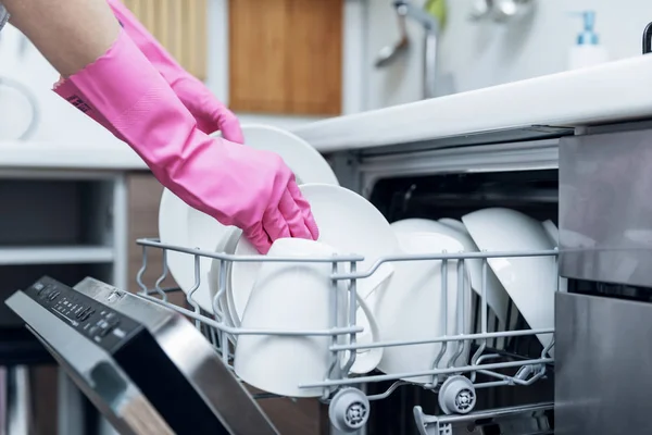 Ama de casa sacando vajilla limpia de lavavajillas en la cocina casera —  Fotos de Stock