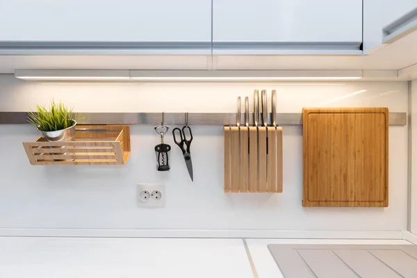 Utensílios de cozinha pendurados no trilho na cozinha branca brilhante — Fotografia de Stock
