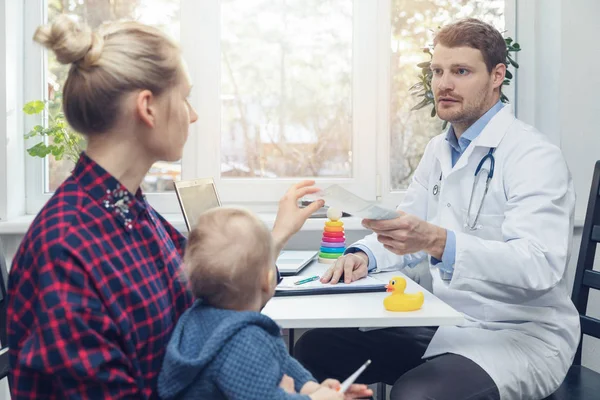 Pédiatre donne une ordonnance à la mère après la consultation — Photo