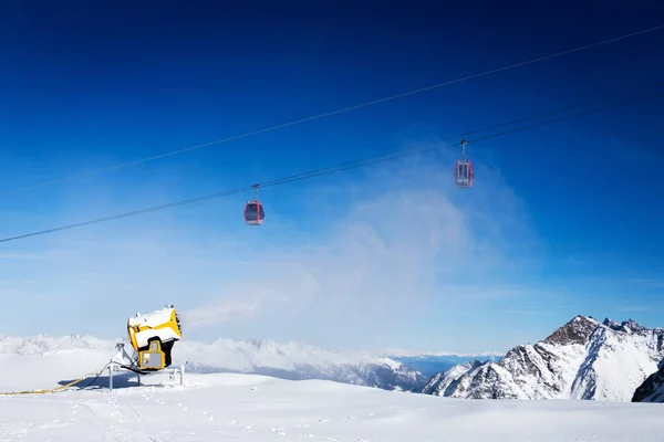 Snow gun working against blue sunny sky at ski resort — Stock Photo, Image