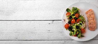 taze salata karışımı ile beyaz ahşap masa üzerinde ızgara somon fileto