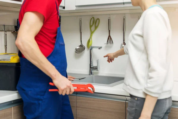 Huisvrouw toont gebroken water kraan loodgieter op huis keuken — Stockfoto