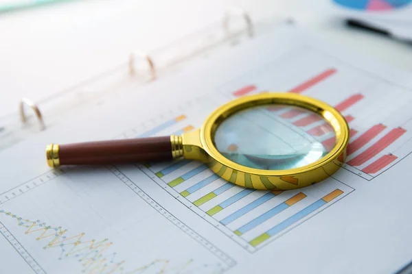 Auditoria empresarial - lupa no relatório gráfico financeiro — Fotografia de Stock