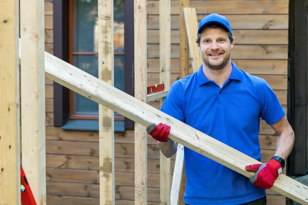 Trabajador con tablón de madera en las manos en la obra — Foto de Stock