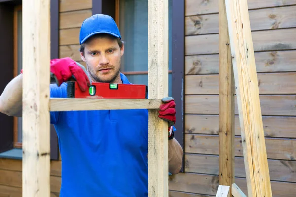 Stavební dělník zkontrolovat úroveň dřevěný rám — Stock fotografie