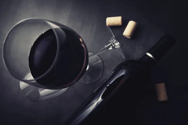 Бутылка красного вина и стакан на черном мраморном фоне. топ — стоковое фото