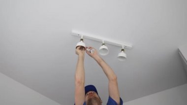 Elektrikçi tavan lambasına ampul yerleştiriyor