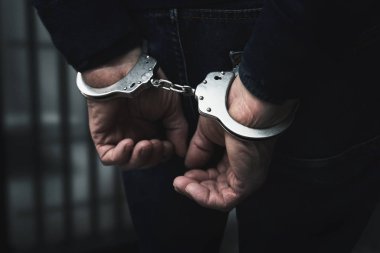 Hapiste elleri kelepçeli tutuklu bir adam var.