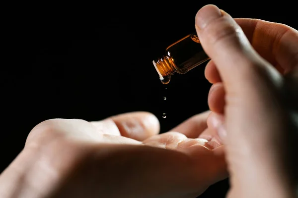 Péče o pleť a ošetření - žena nalévá olej do ruky z injekční lahvičky — Stock fotografie