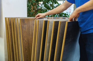 Döşeme dükkanındaki evi için zemin katını seçen bir adam.