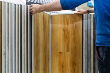 Döşeme dükkanındaki evi için zemin katını seçen bir adam.