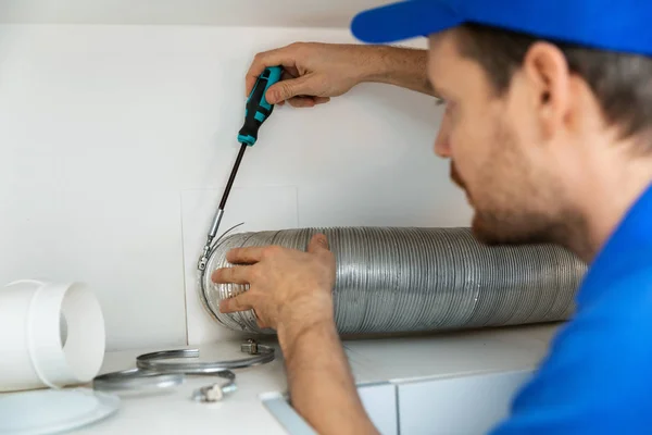 Trabalhador instalando tubo de ventilação de alumínio flexível para cozinha — Fotografia de Stock