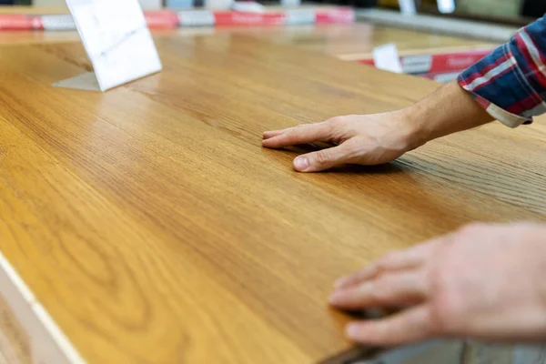 Man vidrör trä textur av laminat golvprov i golv s — Stockfoto