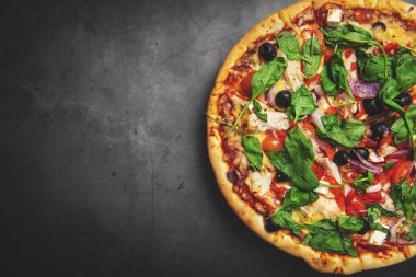 greek chicken pizza on black stone background with copy space. top view