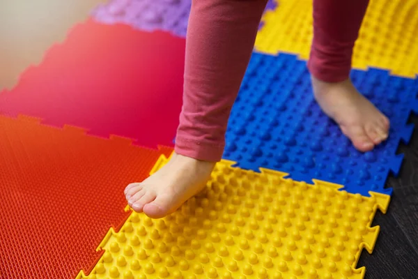 Child walking on orthopedic feet massage puzzle floor mat — Stockfoto