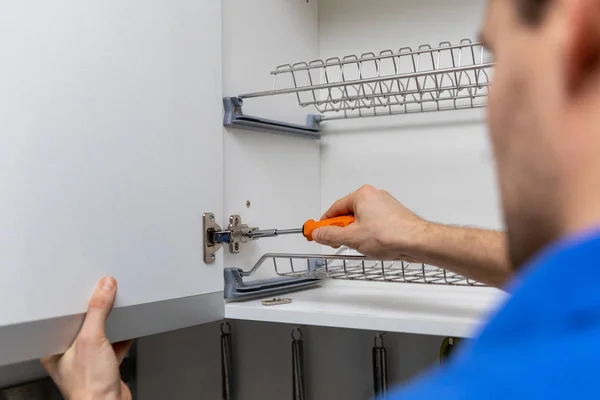 Handyman doing kitchen cabinet hinge adjustment — Stock Photo, Image