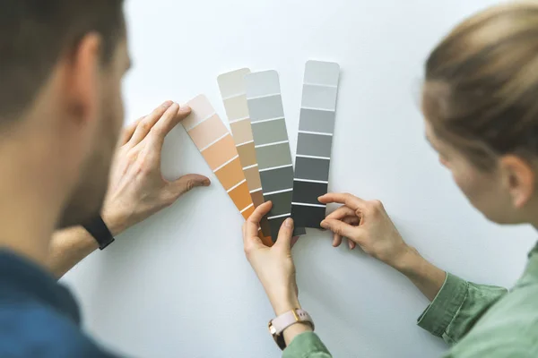 Pareja joven que elige el color de la pintura de las muestras para el nuevo diseño interior del hogar — Foto de Stock
