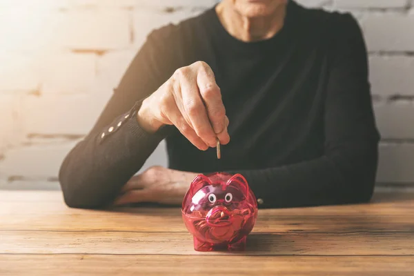 Пенсійні заощадження - старша жінка кладе монету в скарбничку — стокове фото