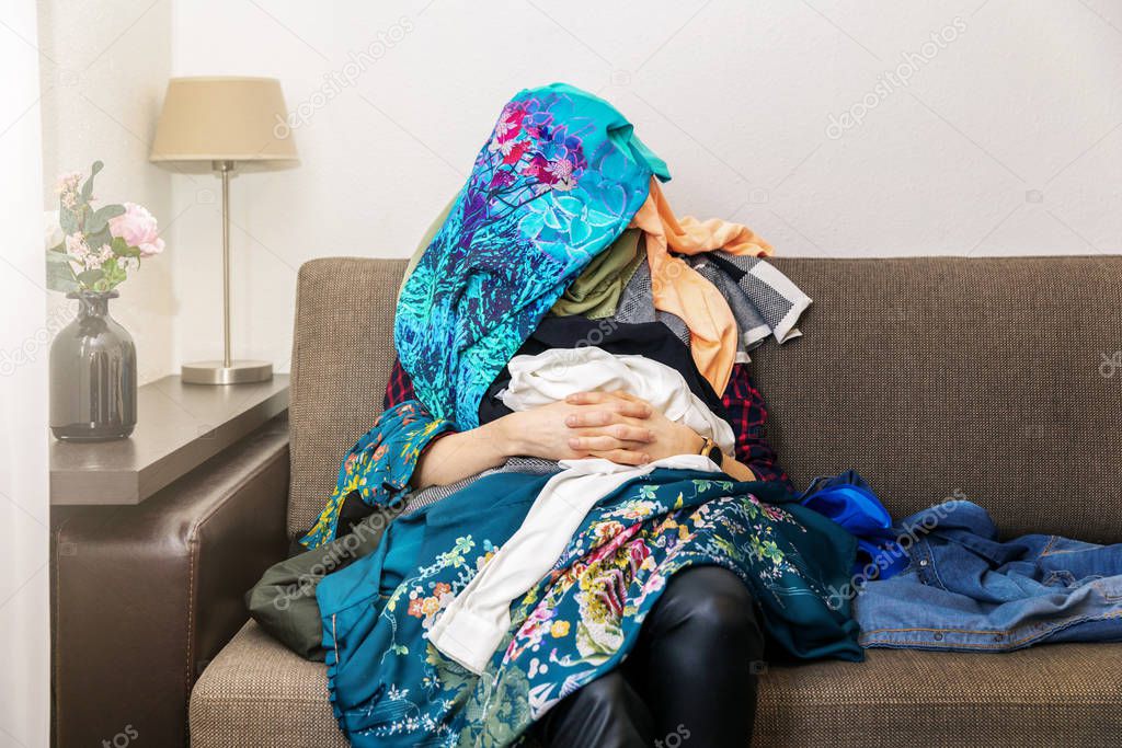 greedy shopping obsessed woman sitting on couch with clothes hea