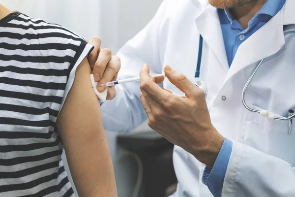 Lekarz podający pacjentowi szczepionkę przeciwko grypie w klinice — Zdjęcie stockowe